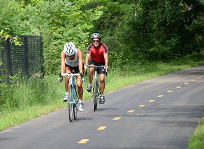 Two people riding bicycles on a paved trail.
