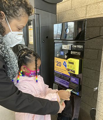 Customers buying transit tickets at a self-service machine.
