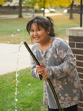A child holding a hose with water streaming out.
